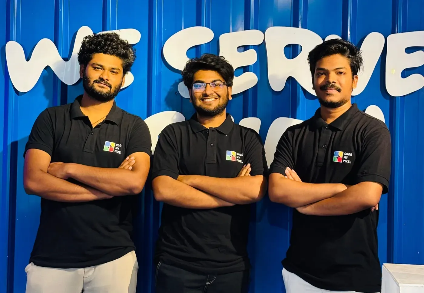 Three CodeMyPixel executives in branded polos, arms folded, against a painted wall.